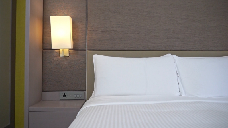 Uredan krevet sa belom posteljinom koji pokazuje jednostavan i funkcionalan prostor za spavanje