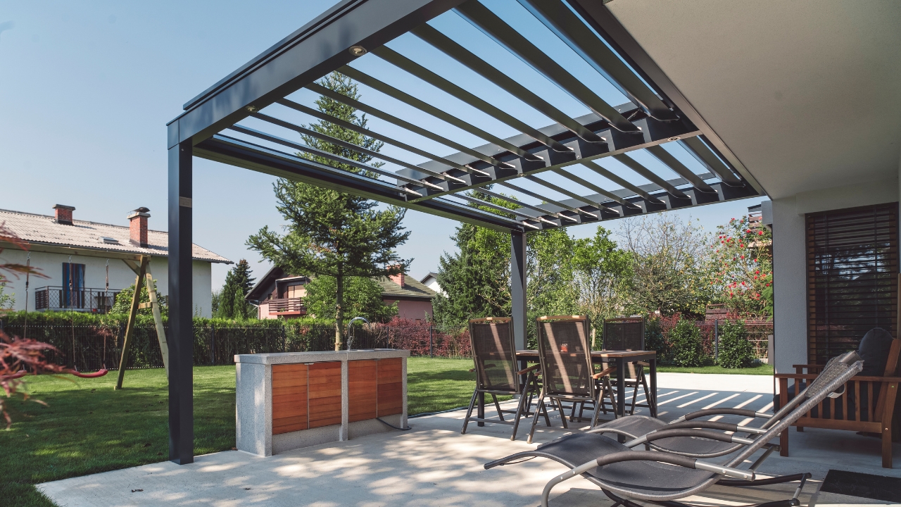 Metalna pergola sa prostorom za sedenje uz moderno uređeno dvorište