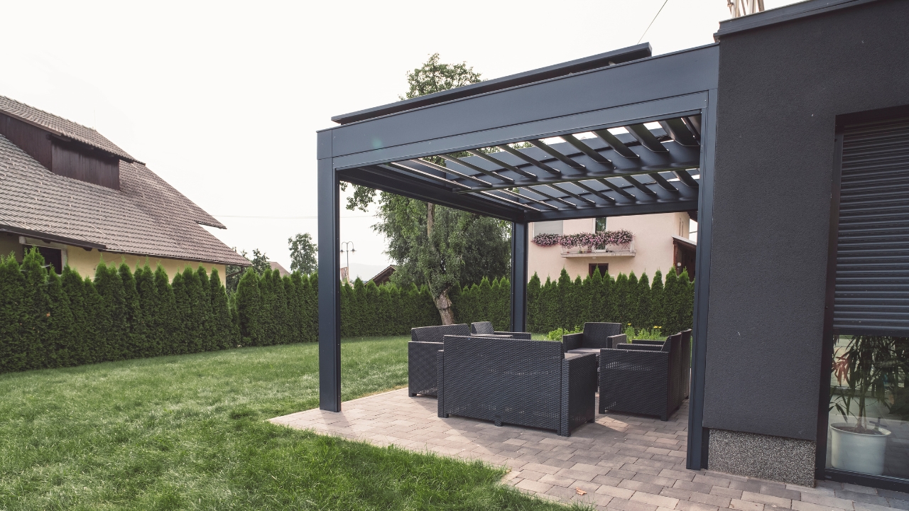 Moderna pergola sa garniturom za sedenje uz uređeno dvorište i kuću